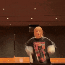 a woman is standing on a stage with her arms outstretched and a cat on her shirt .