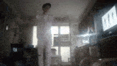 a man is dancing in a living room with a tv in the background