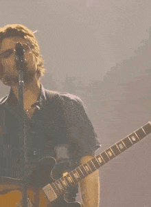 a man sings into a microphone while playing a guitar
