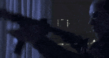 a man is holding a gun in a dark room .