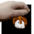 a hand is holding a cartoon character 's head with a smile on it .