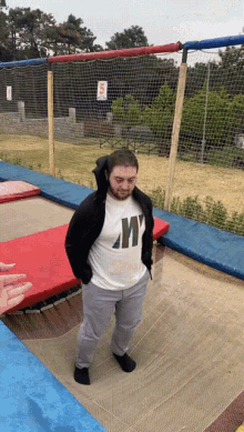a man standing on a trampoline wearing a shirt with the letter w on it
