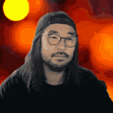a man with long hair and glasses is wearing a hat