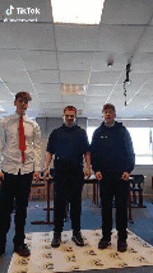three young men are standing in a room with tiktok written on the bottom right corner