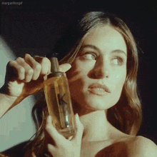 a woman is holding a bottle of perfume and looking at it