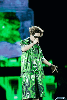 a man wearing a green shirt and shorts sings into a microphone