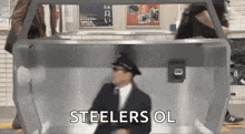 a man in a suit and hat is dancing in a subway station with the words `` steelers ol '' .