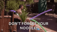 a man is sitting in a hot tub with a plant and balloons flying in the air .