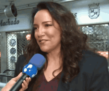 a woman is holding a blue microphone in front of a machado sign