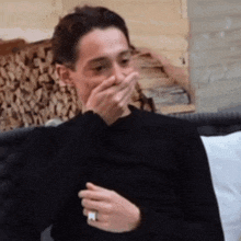 a man in a black shirt is covering his mouth with his hand