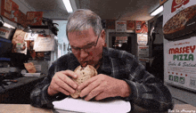 a man is eating a sandwich in front of massey pizza signs