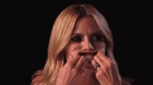a woman is making a funny face while holding her hands to her mouth .