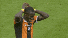 a soccer player wearing an orange and black jersey with the word sportpesa on the front