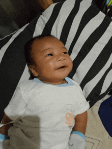 a baby is laying on a black and white striped pillow and wearing a shirt that says ' baby ' on it
