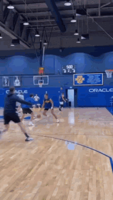 a basketball game is being played in a gym with oracle written on the wall