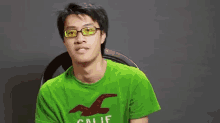 a man wearing glasses is wearing a green hollister shirt