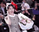 a woman wearing a cat ear headband is holding a bouquet of flowers