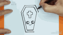 a person is drawing a coffin with a cross and a face on it