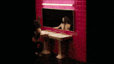 a woman looks at her reflection in a mirror in a bathroom