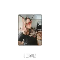 a woman wearing sunglasses and a black shirt with the words i am in
