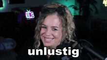 a woman is smiling in front of a microphone and the word unlustig is on the screen behind her