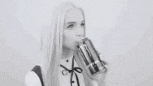 a black and white photo of a woman drinking a can of soda .