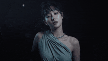 a woman in a blue dress with a necklace on her neck