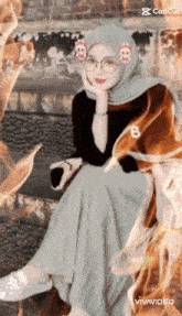 a woman wearing a hijab and glasses is sitting in a chair .