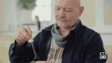 a man is holding a bottle with a dropper in his hand .