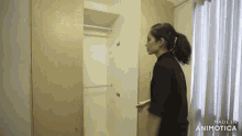 a woman in a black shirt is standing in front of a wardrobe .