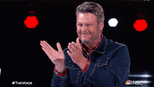 a man in a denim jacket is applauding on nbc 's the voice