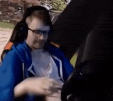 a man wearing headphones and glasses is sitting in a chair and talking to someone .