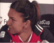 a woman wearing a red cup shirt looks to the side