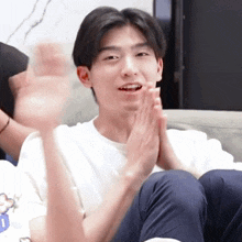 a young man sitting on a couch with his hands folded