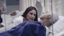 a woman is talking to an elderly man laying in a hospital bed .