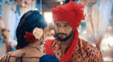a man in a red turban looks at a woman