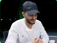 a man with a beard is wearing a black hat and a white shirt .