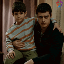 a boy sits on a man 's lap with a star on the bottom right