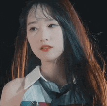 a close up of a woman 's face with long hair and a white shirt