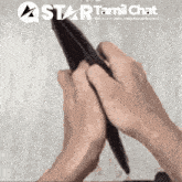 a person is holding a pen in front of a star tamil chat sign
