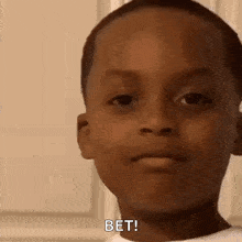 a young boy is making a funny face while looking at the camera .