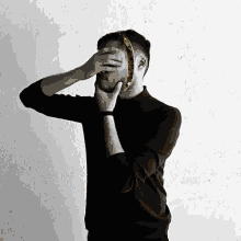 a man in a black shirt covering his face with a banana