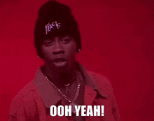 a man wearing a pink jacket and a black beanie is saying ooh yeah