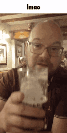 a bald man with glasses is drinking from a glass with the word lmao above him