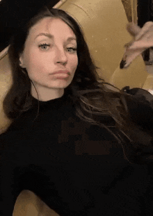 a woman in a black shirt is sitting on a couch and making a face .