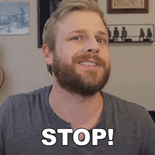 a man with a beard is smiling and says stop in white letters