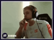 a man wearing headphones is sitting in a chair with his hand to his mouth .