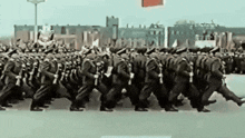 a large group of soldiers marching down a street in a parade .