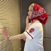 a woman wearing a red bandana on her head is looking out a window