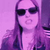 a woman wearing sunglasses and headphones is making a funny face in a purple room .
